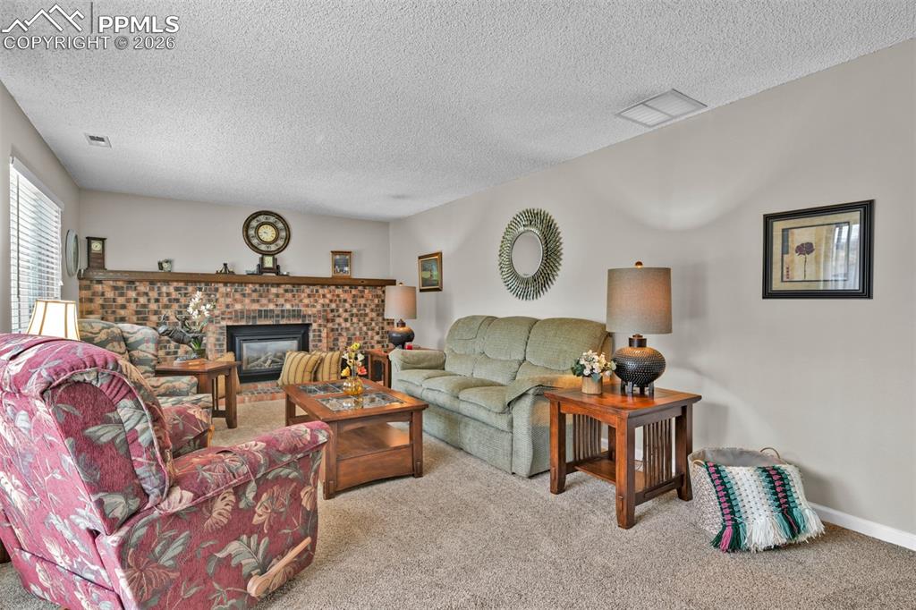 Image 36 of 41: Living area featuring carpet, a fireplace, and a textured ceiling