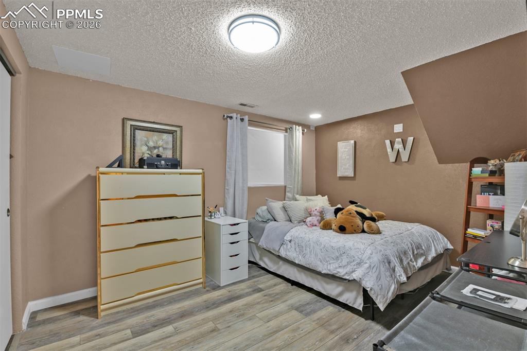 Image 40 of 41: Bedroom featuring light wood-type flooring and a textured ceiling