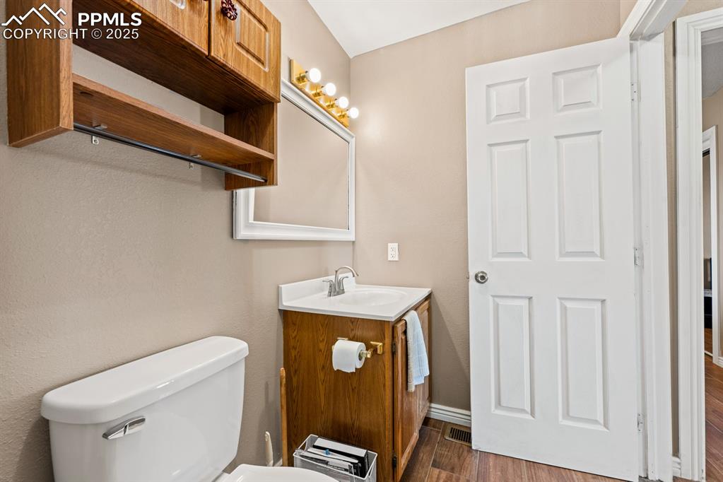 Image 18 of 39: Bathroom with toilet, vanity, and wood finished floors