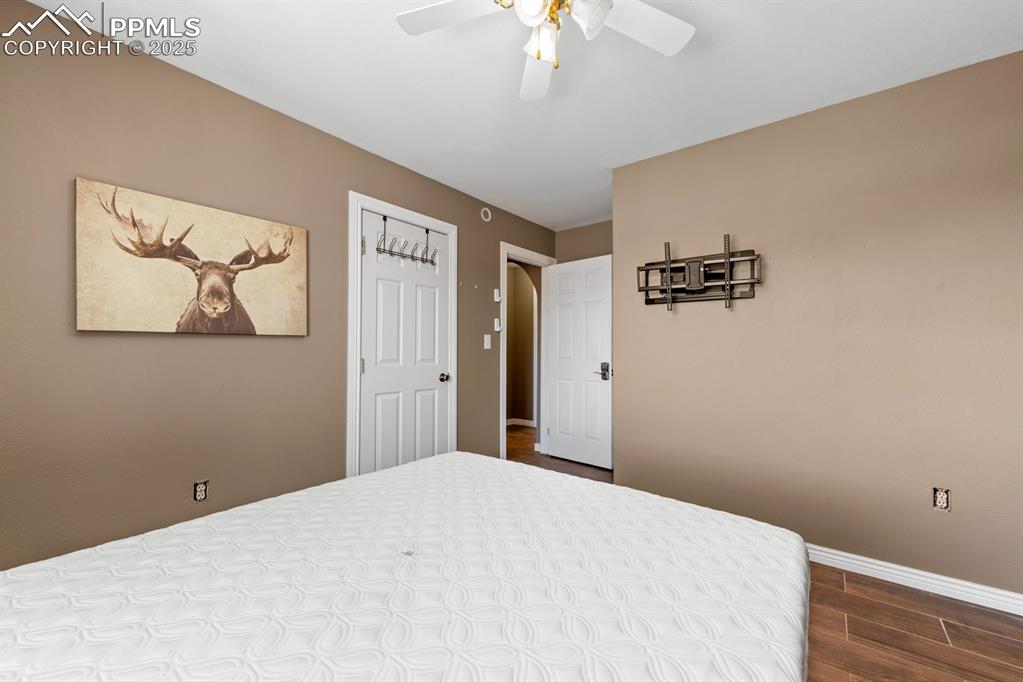 Image 20 of 39: Bedroom with dark wood-style tile flooring, and ceiling fan