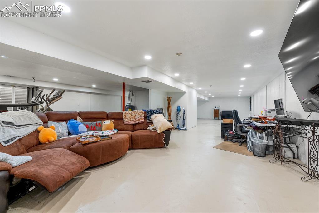 Image 24 of 39: Basement living area featuring recessed lighting, concrete flooring, and an