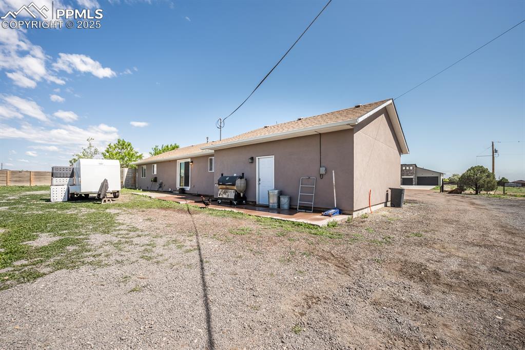 Image 29 of 39: Rear view of house with stucco siding and a patio