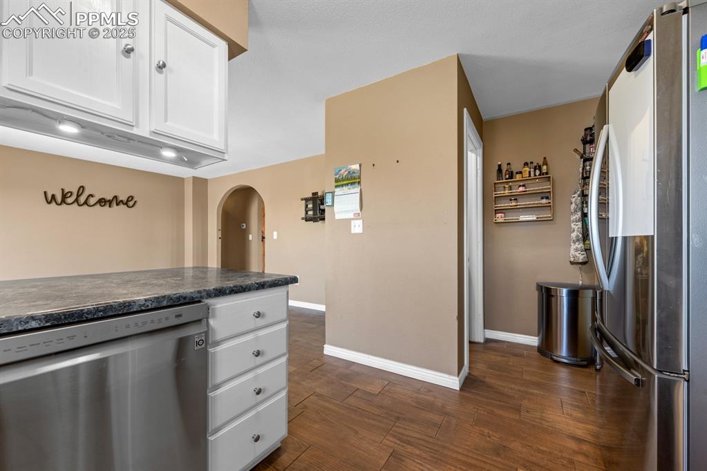 Image 8 of 39: Kitchen with appliances with stainless steel finishes, arched walkways, bas