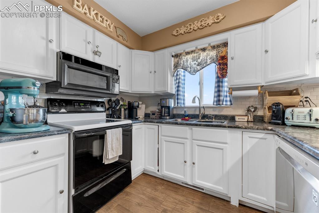Image 9 of 39: Kitchen with electric range oven, black microwave, dishwasher, a sink, and