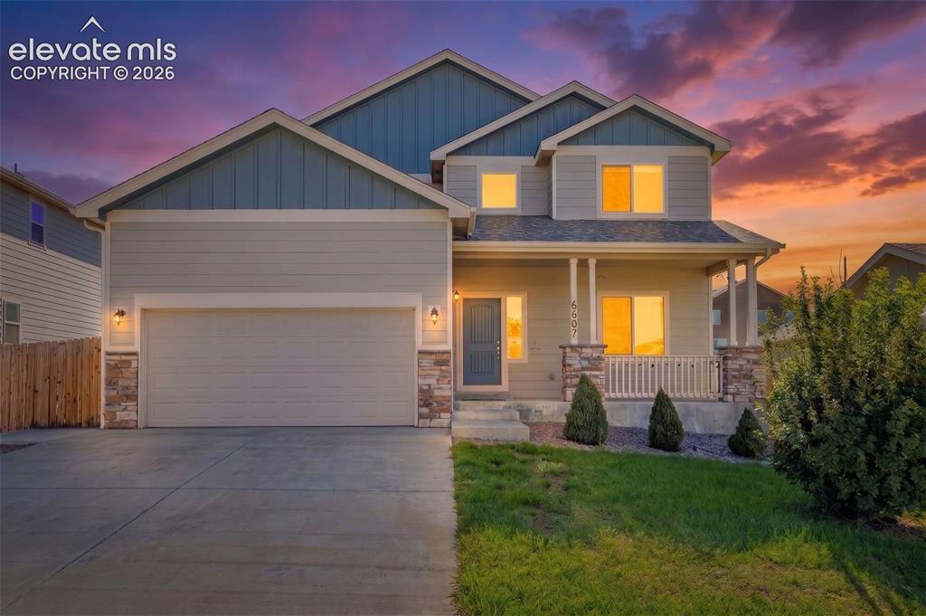 Caption: Two-story residence featuring a covered front porch with white railing, stone accents, and a two-car