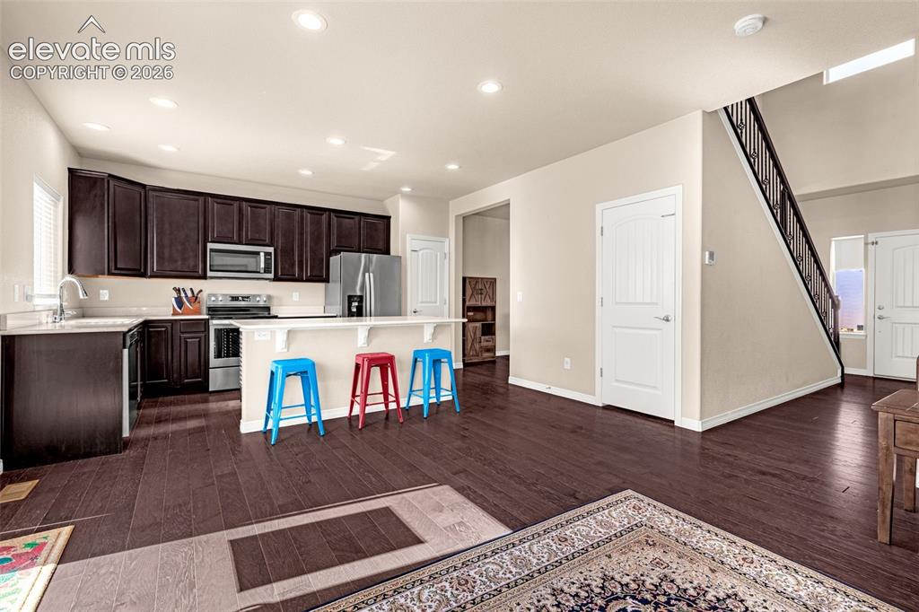 Image 11 of 45: Kitchen featuring dark wood cabinetry, stainless steel appliances, and an i
