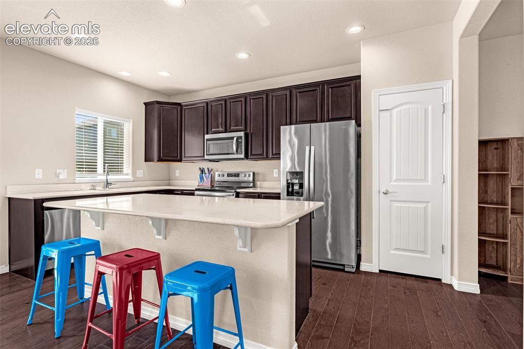 Image 12 of 45: Kitchen featuring wood-finish flooring, recessed lighting, dark wood cabine