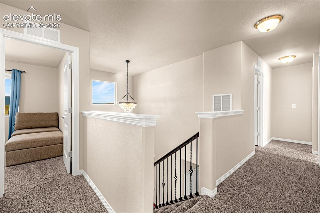 Image 16 of 45: Carpeted hallway with a decorative chandelier, recessed lighting, and a win