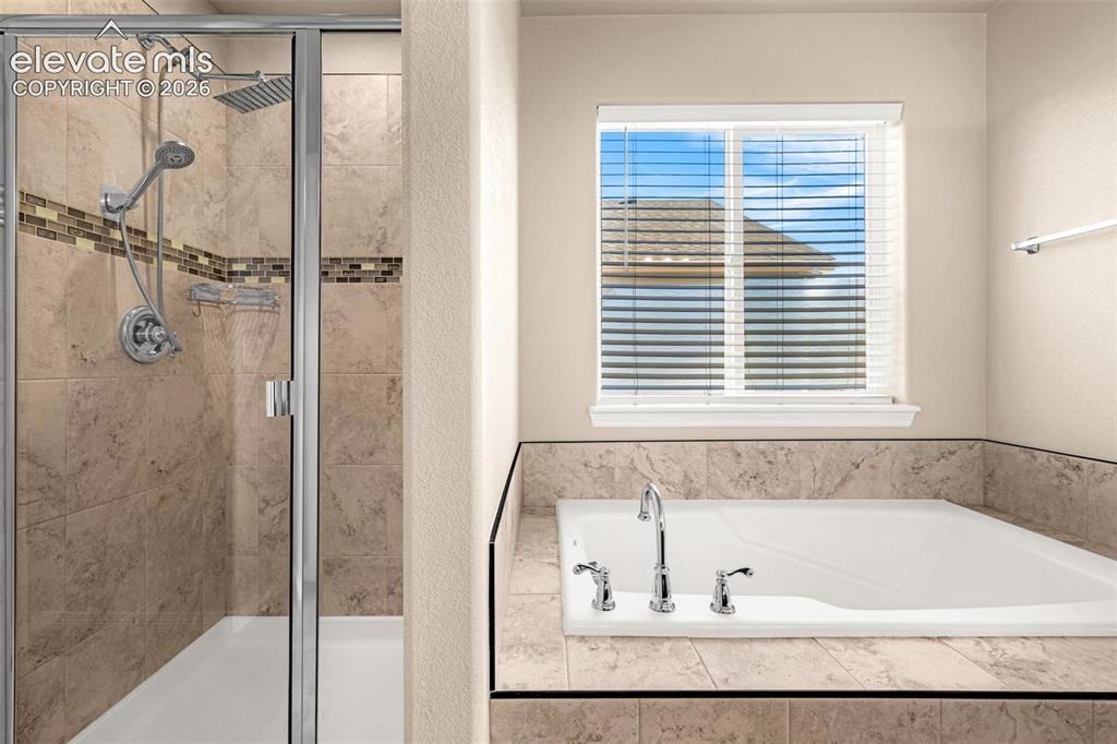 Image 19 of 45: Tiled walk-in shower with glass enclosure, dual shower heads, and decorativ