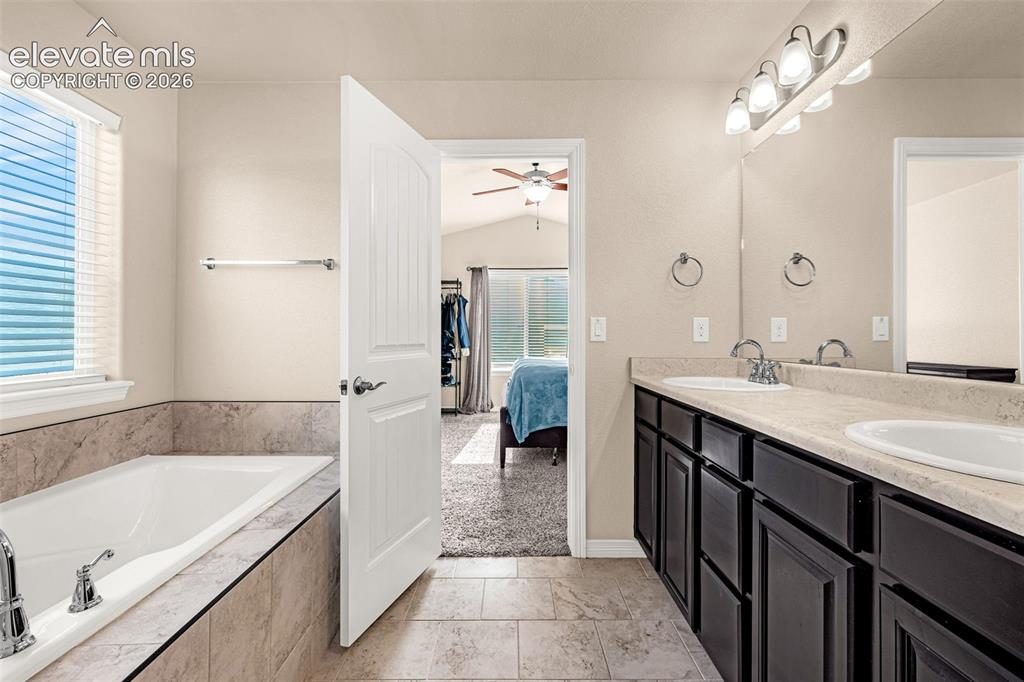 Image 21 of 45: Soaking tub with tile surround, dual vanity with undermount sinks, wood-fin