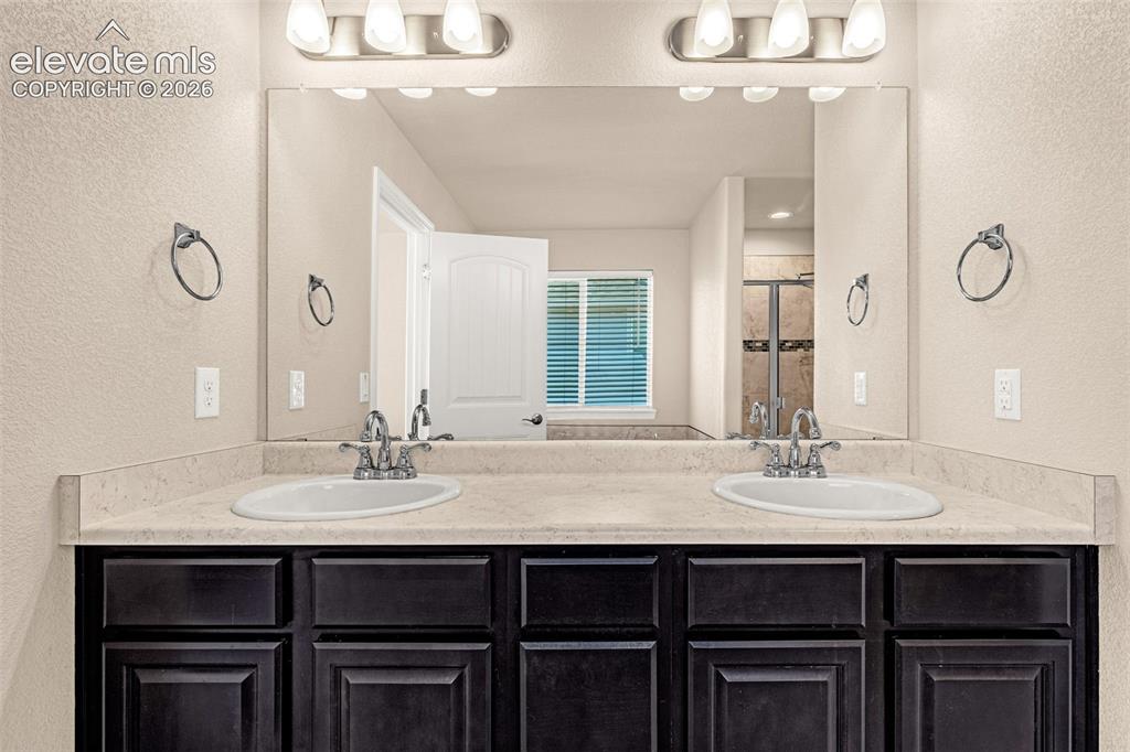 Image 23 of 45: Dual vanity with integrated sinks, light-toned countertop, dark wood-finish