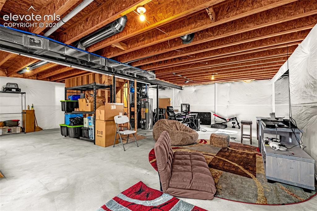 Image 29 of 45: Unfinished basement with concrete flooring and exposed wood ceiling joists