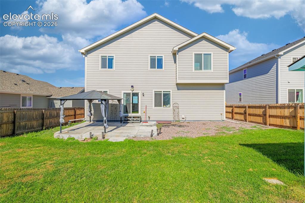 Image 31 of 45: Expansive backyard with a manicured lawn, concrete patio, and privacy fenci