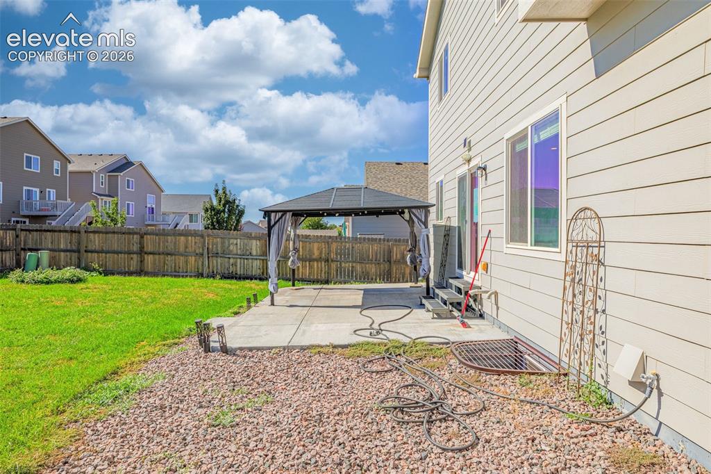 Image 33 of 45: Expansive backyard with a level lawn, concrete patio, and privacy fencing