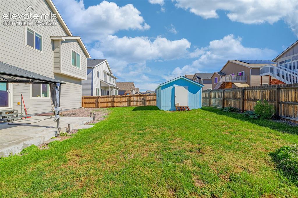 Image 34 of 45: Expansive green lawn with a privacy fence and a detached storage shed