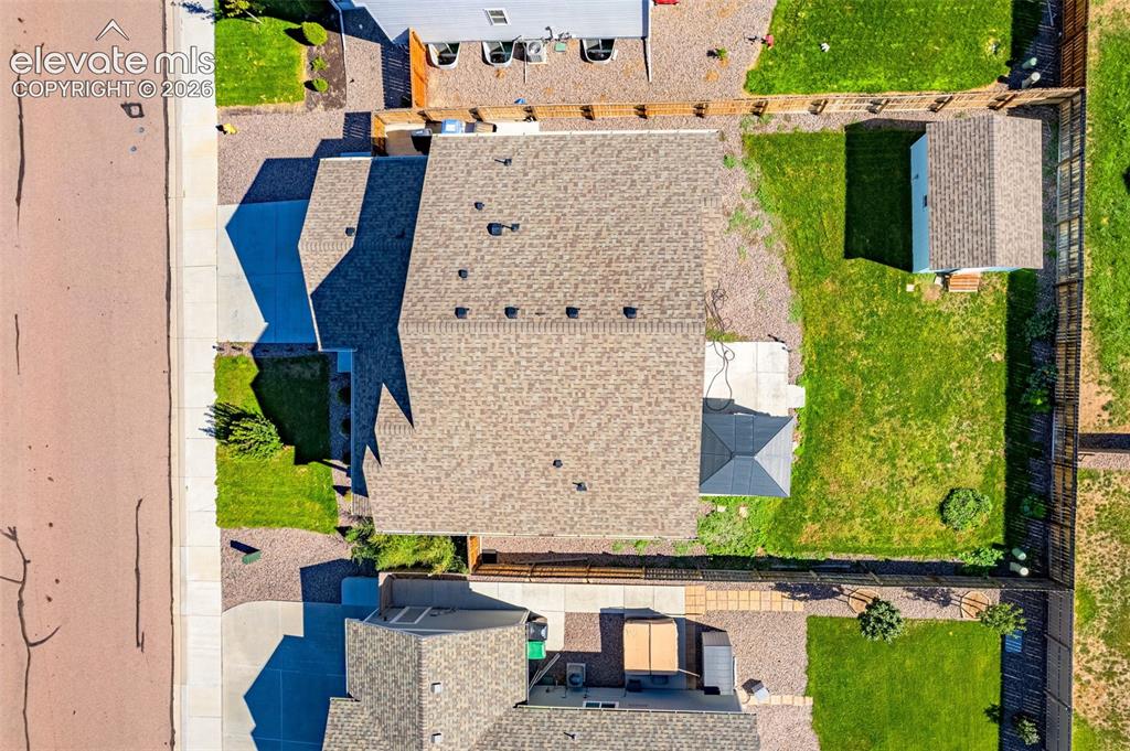 Image 36 of 45: Paved driveway leading to a shingled roof property, featuring a fenced back