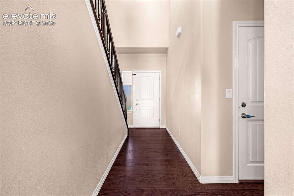 Image 5 of 45: Entryway featuring dark wood-finish flooring, light-toned walls, and a stai