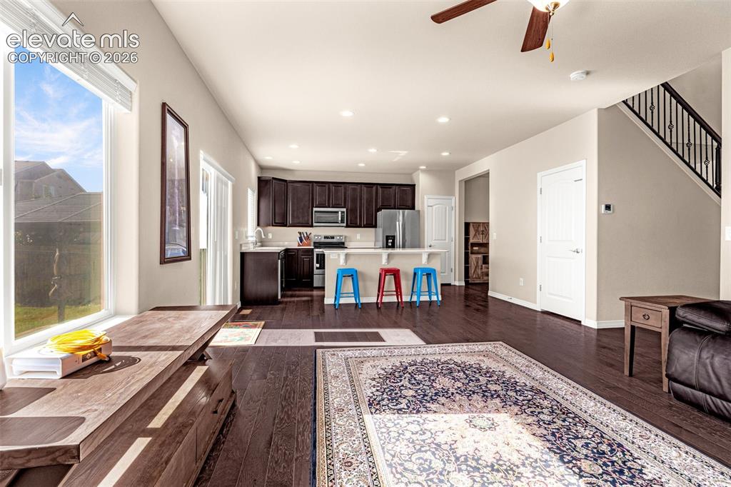 Image 9 of 45: Open-concept living space with dark wood-finish flooring, recessed lighting