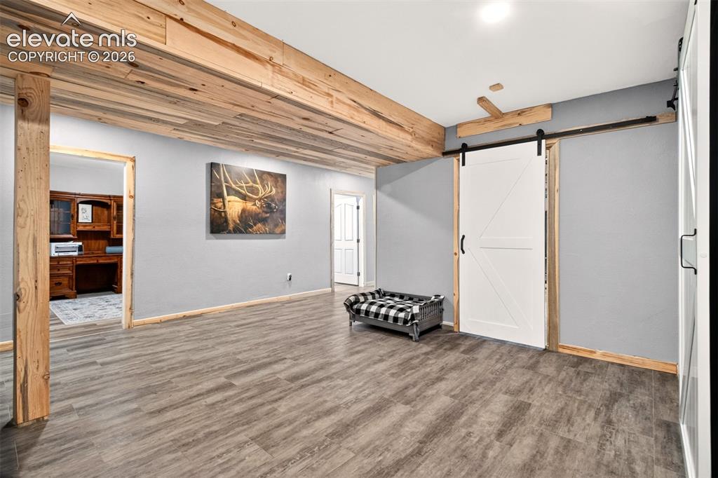 Image 24 of 50: Fully finished, expansive basement showcasing striking beetle kill pine acc