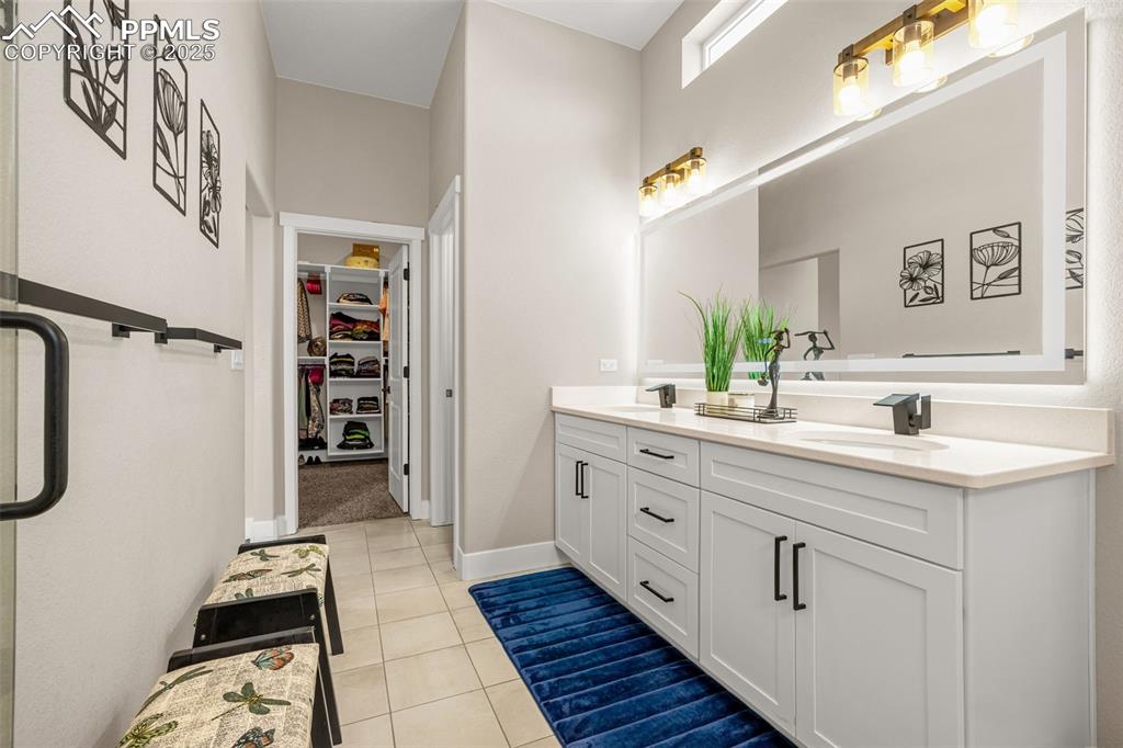 Image 13 of 35: Bathroom featuring double vanity, tile patterned floors, and a spacious clo