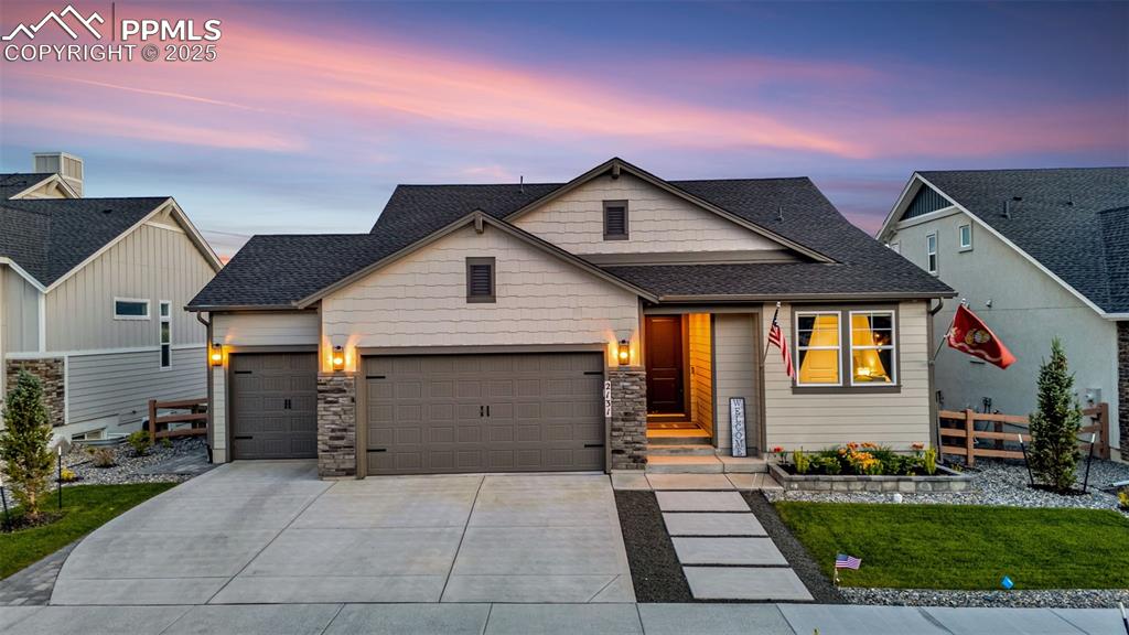 Image 32 of 35: View of front of property with a garage, driveway, stone siding, and a shin