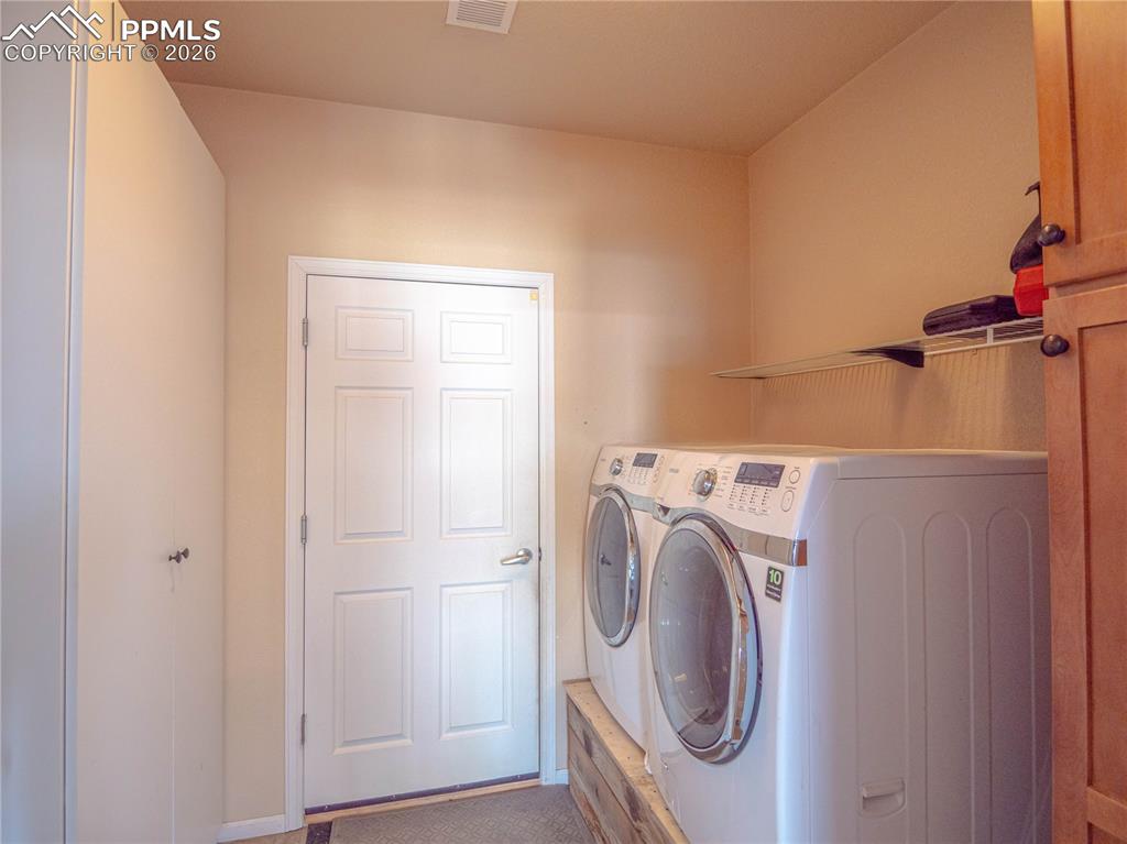 Image 10 of 17: Laundry area featuring a paneled door, built-in shelving, and light-toned w