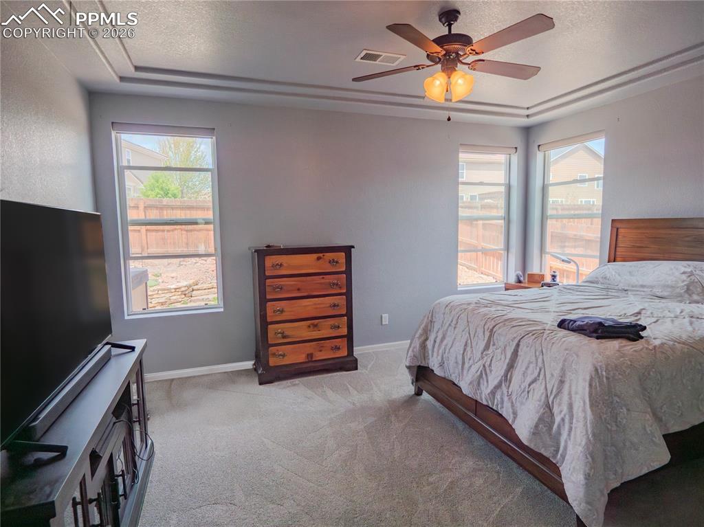 Image 11 of 17: Spacious room featuring a tray ceiling, ceiling fan with integrated lightin