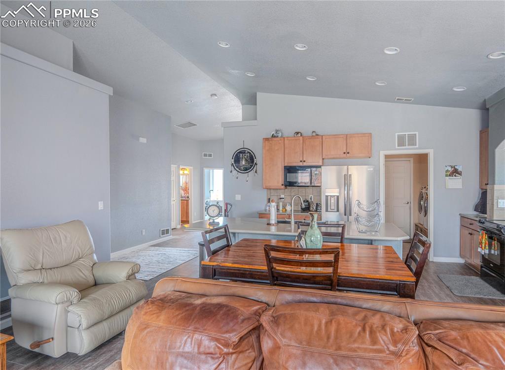 Image 7 of 17: Open-concept living space featuring vaulted ceilings, recessed lighting, an
