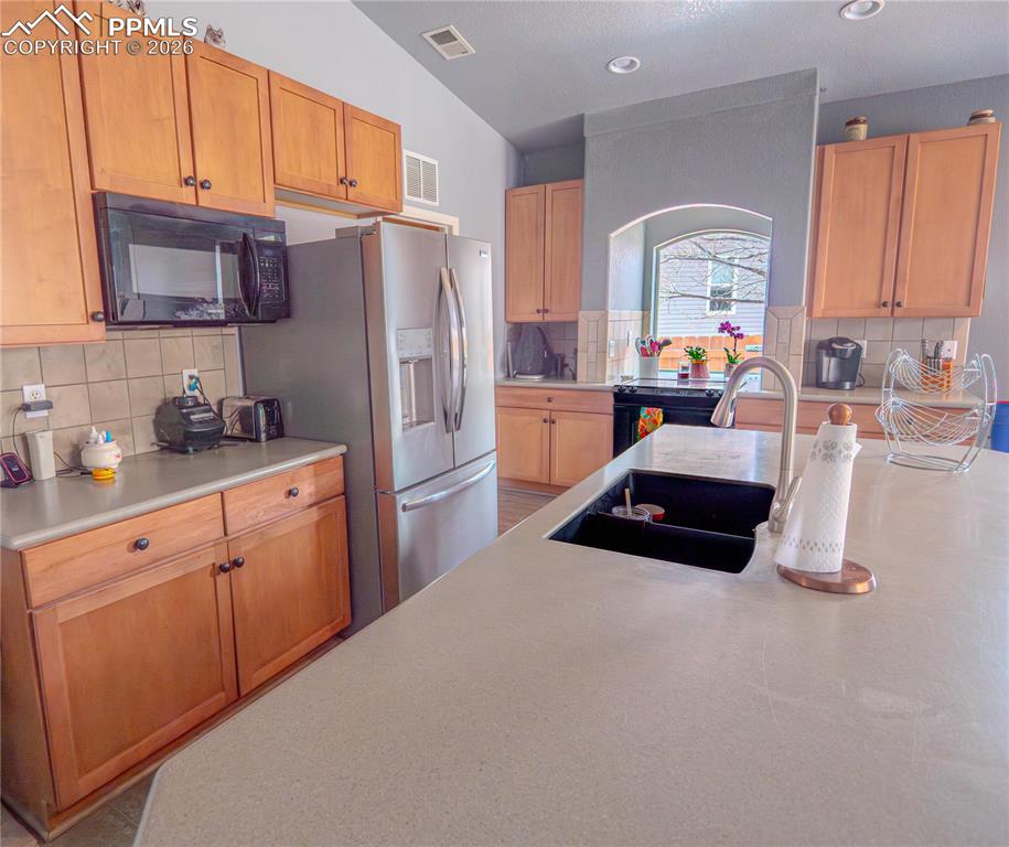Image 8 of 17: Kitchen featuring a large island with an integrated black sink, wood-finish