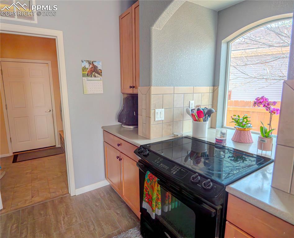 Image 9 of 17: Kitchen featuring a black electric range, light wood-finish cabinetry, a ti