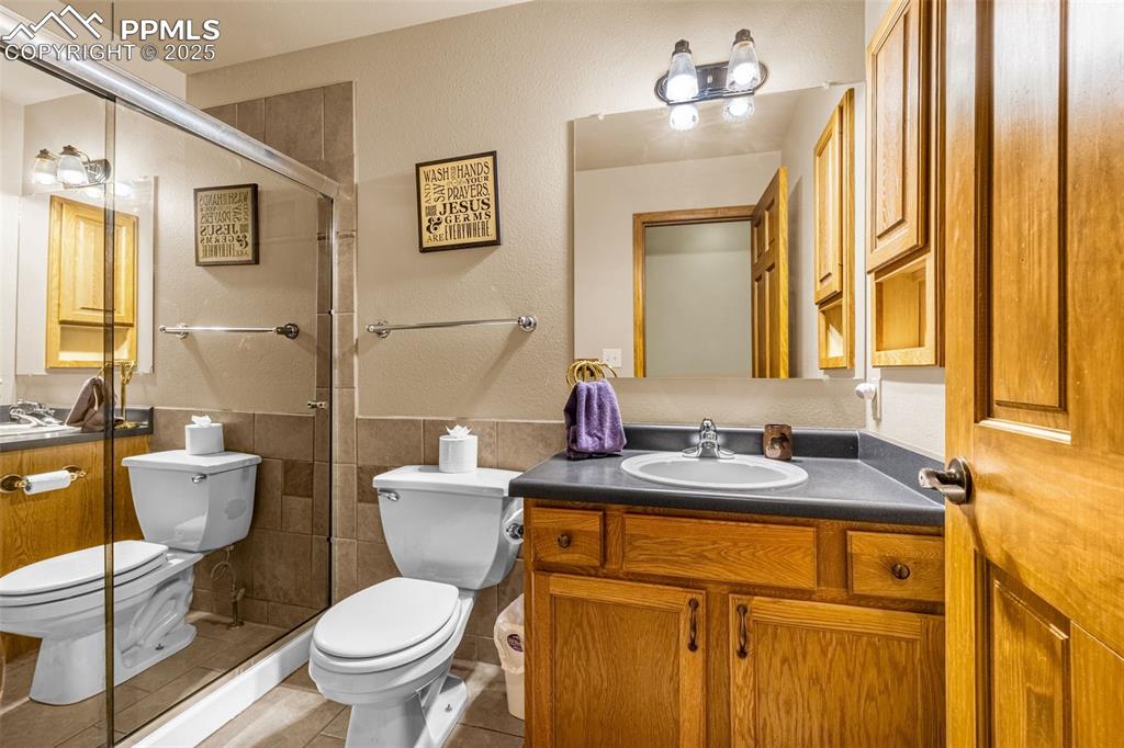 Image 22 of 36: Full bathroom featuring tile walls, tile patterned flooring, vanity, a tile