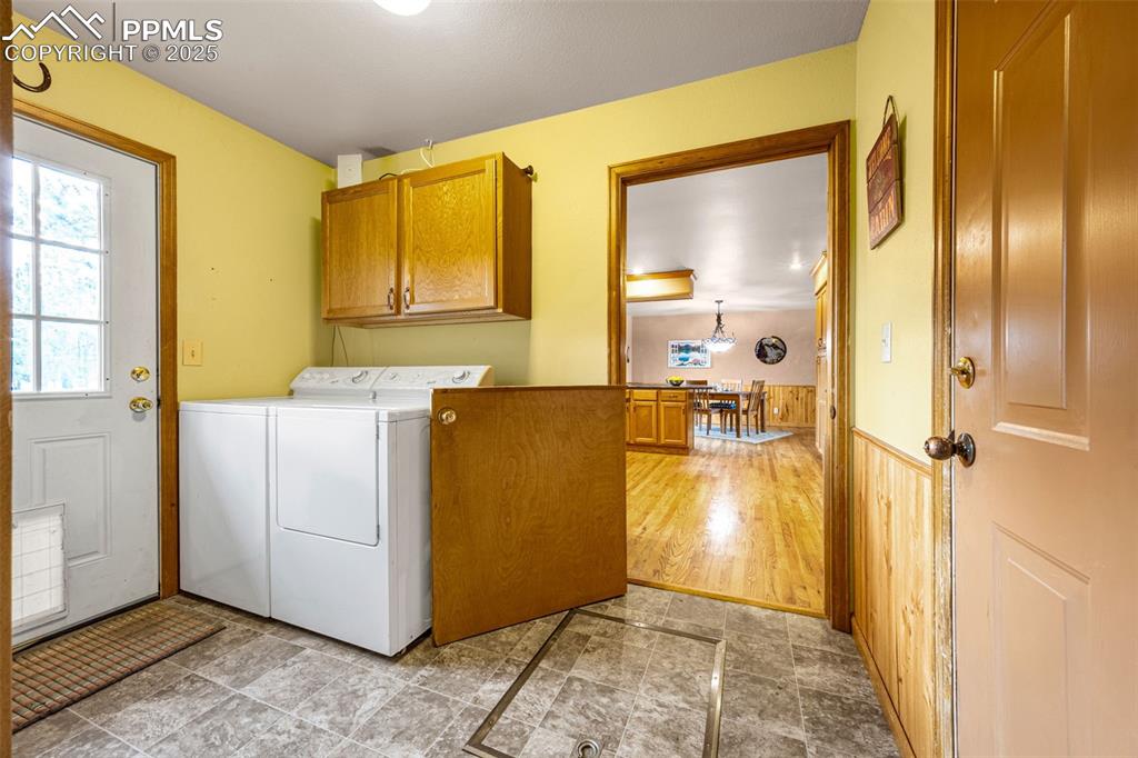 Image 23 of 36: Washroom with cabinet space, washer and clothes dryer, and wainscoting