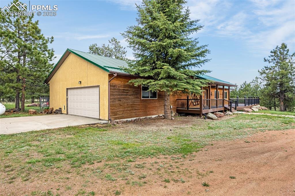 Image 28 of 36: View of property exterior featuring a metal roof, a deck, and a lawn