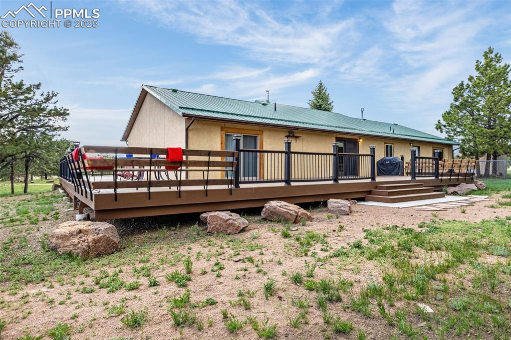 Image 3 of 36: Back of house featuring a metal roof, a deck, and stucco siding