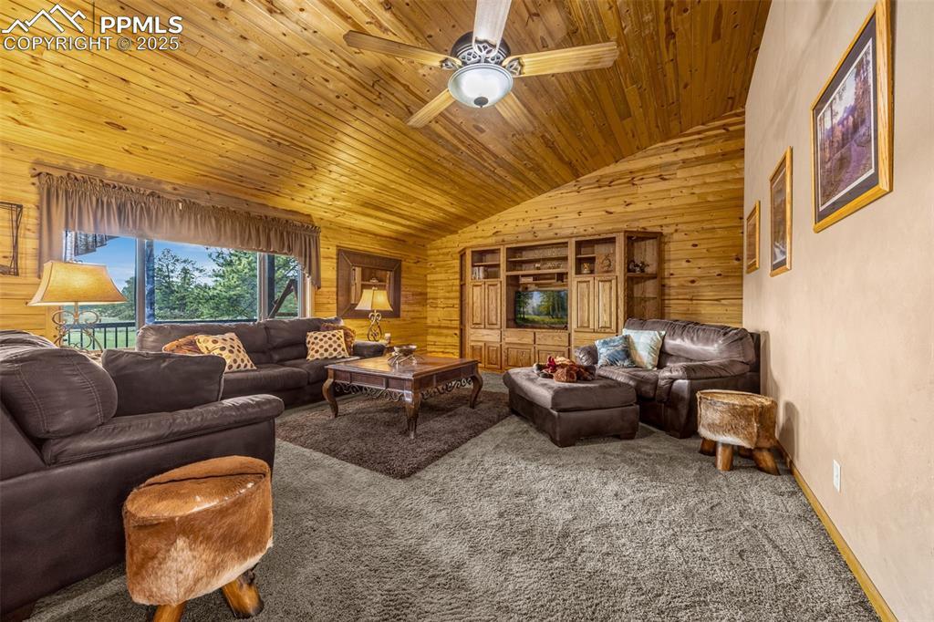 Image 5 of 36: Living room featuring wooden ceiling, carpet, vaulted ceiling, wood walls,