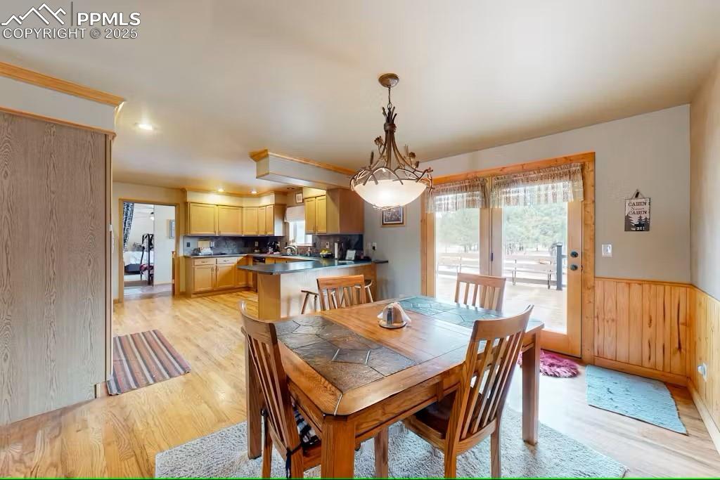 Image 9 of 36: Dining area featuring light wood-type flooring, wood walls, and a wainscote