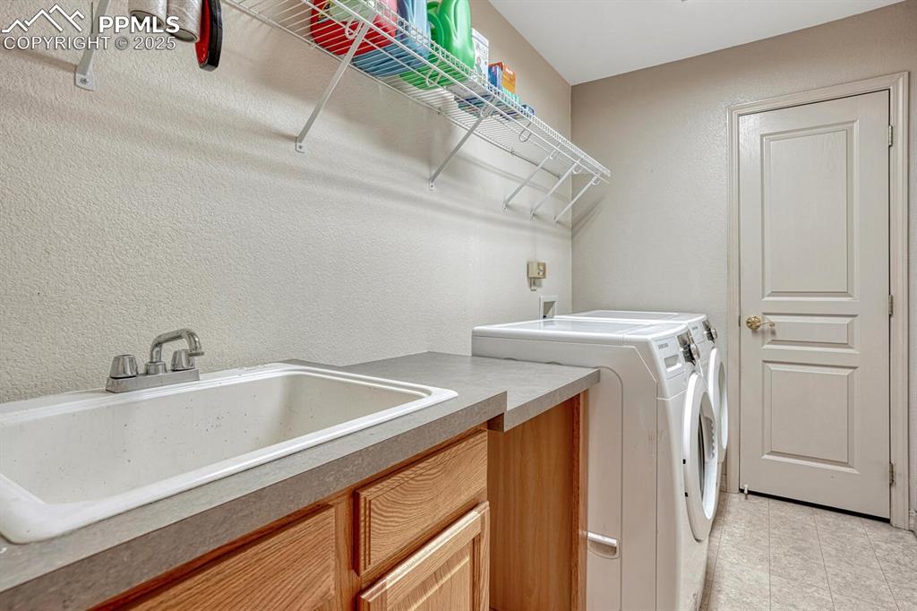 Image 13 of 50: Main level Laundry Room with cabinet, built-in shelf, and sink.