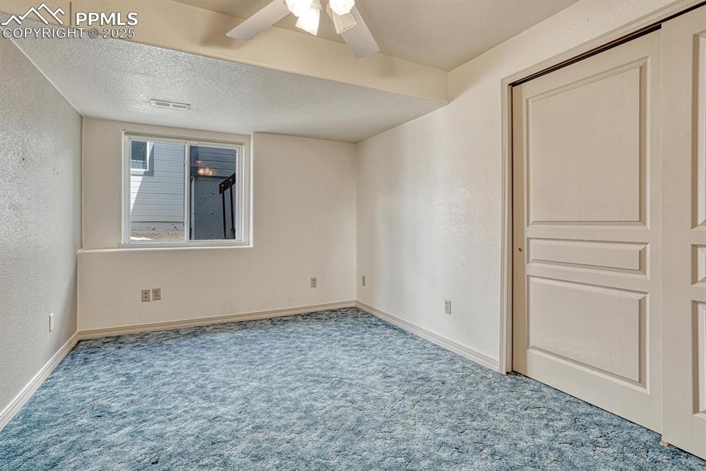Image 38 of 50: Basement Bedroom #5 with carpet and lighted ceiling fan.