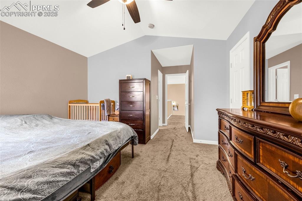 Image 14 of 23: Bedroom with light carpet, vaulted ceiling, baseboards, and a ceiling fan