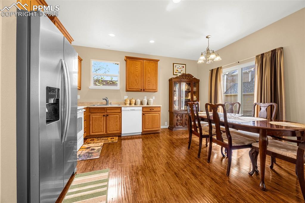Image 5 of 23: Kitchen featuring white appliances, a chandelier, light countertops, dark w