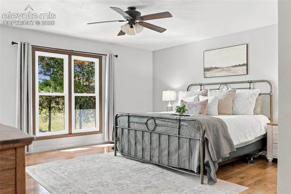 Image 11 of 37: Expansive window with wood-finish trim, wood-finish flooring, ceiling fan w