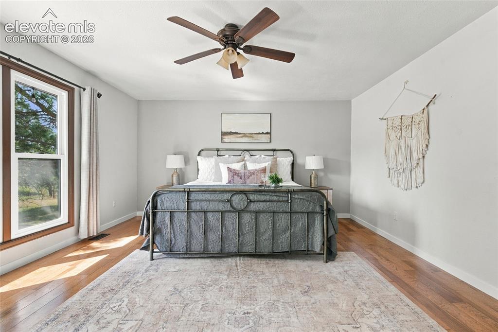 Image 12 of 37: Hardwood flooring, a large window with wood trim, neutral wall tones, and a