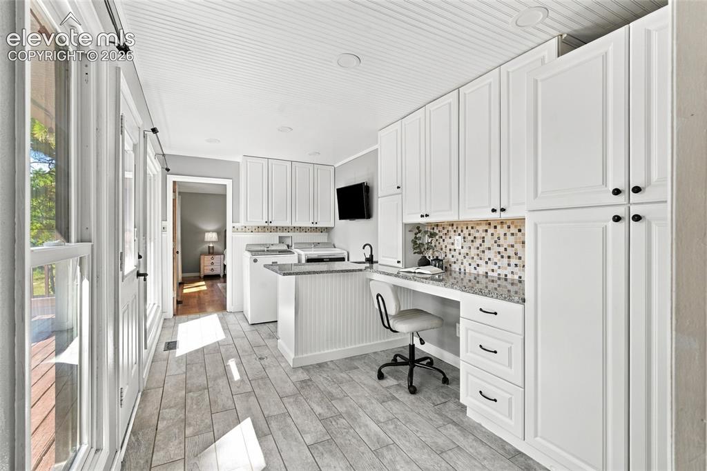 Image 14 of 37: White shaker-style cabinetry with matte black hardware, mosaic tile backspl
