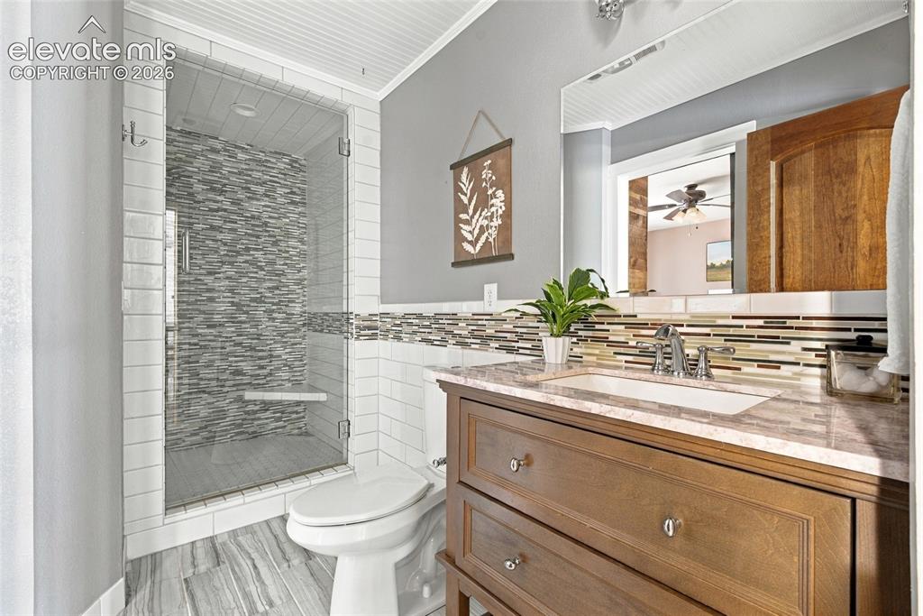 Image 16 of 37: ensuite bathroom Glass-enclosed shower with a mosaic tile wall and built-in