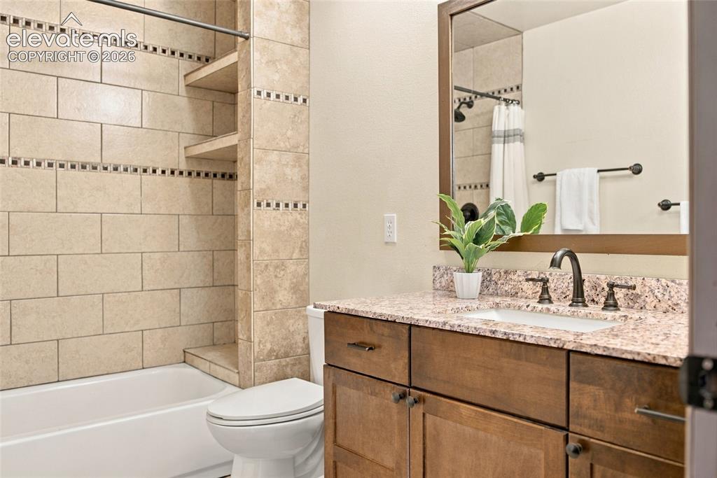 Image 18 of 37: Tub-shower combination with tiled surround, built-in shelving, wood-finish