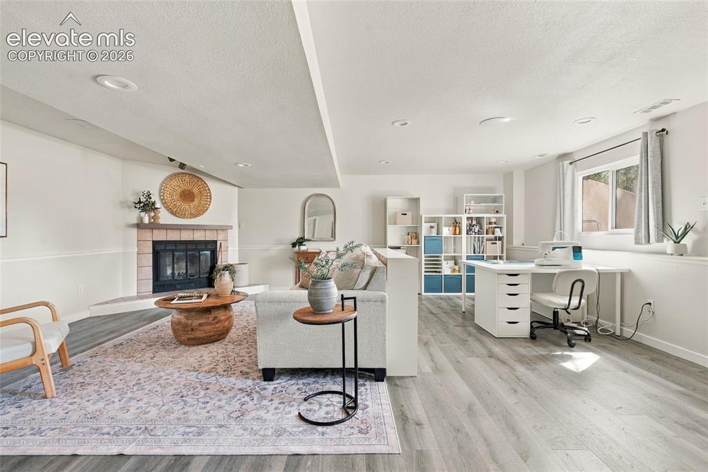 Image 19 of 37: Basement Corner fireplace with a tile surround and hearth