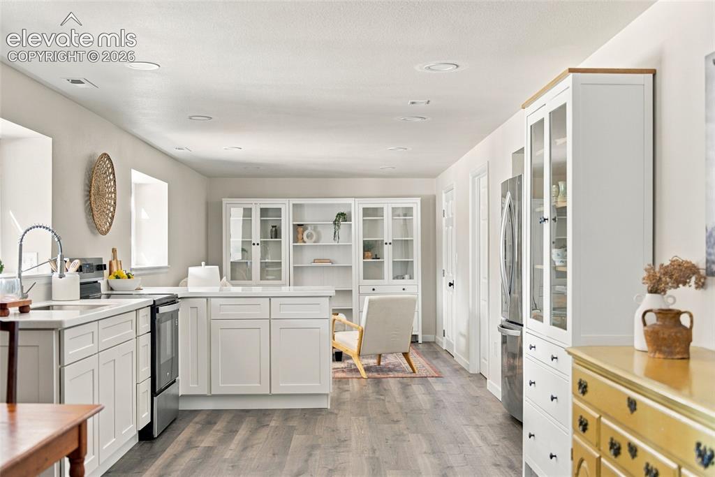 Image 21 of 37: Basement White cabinetry with a center island and stainless steel appliance