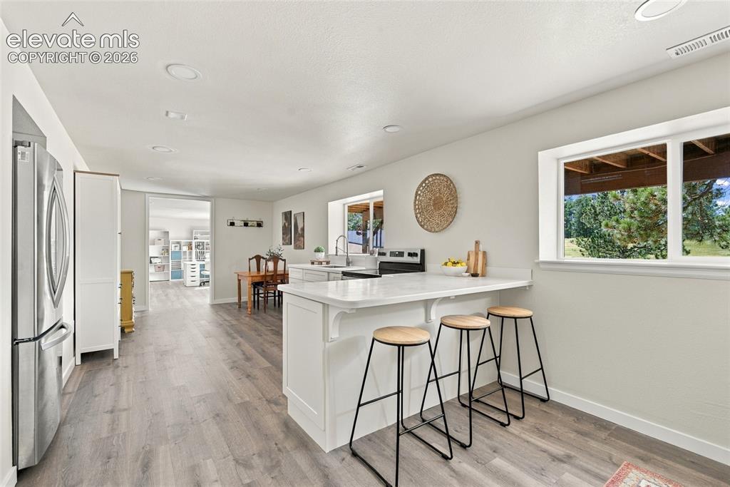 Image 23 of 37: Basement Kitchen with white cabinetry, light countertops, stainless steel a