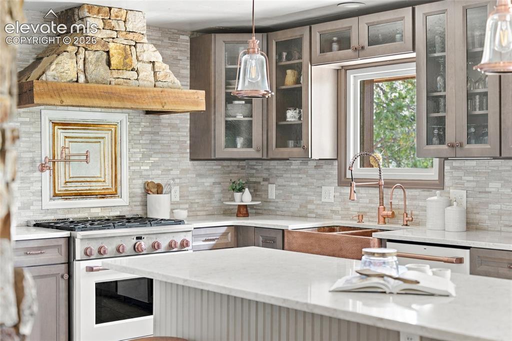 Image 3 of 37: Stone-clad range hood with wood beam accent, full-height tile backsplash, c