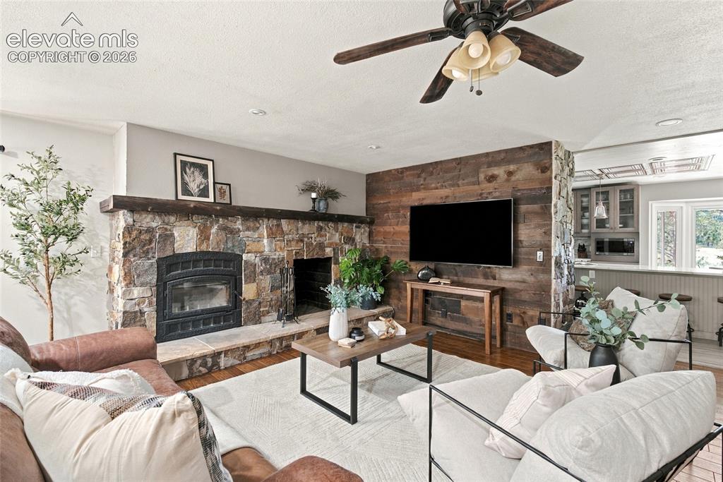 Image 6 of 37: Stone fireplace with wood mantel, wood-finish flooring, wood plank accent w